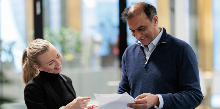 A female and male employee standing and looking at papers