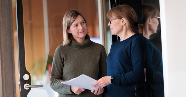 Two female employees standing and holding papers