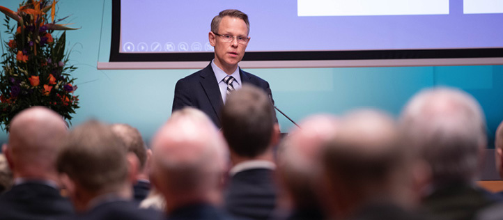 A man standing and speaking in front of a seated audience