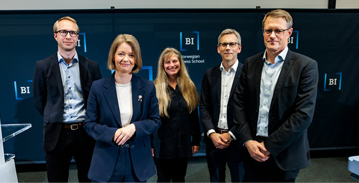 A group of two women and three men standing and looking at the camera