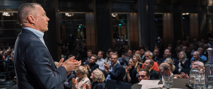 A man standing and speaking in front of a seated audience.