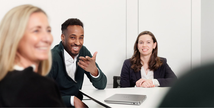 Two female and one male employee discussing while sitting at a table