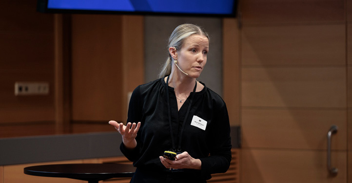 A woman standing giving a speech wearing a headset microphone  