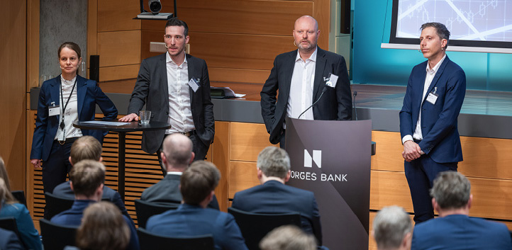 Four men standing in front of an audience in Norges Bank’s auditorium